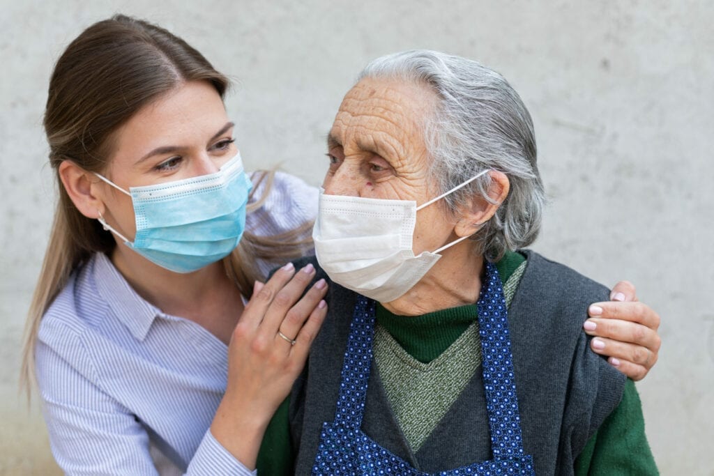 Caregiver with elderly ill woman wearing mask In-Home Caregivers